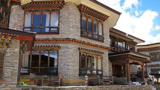 Un bâtiment traditionnel à plusieurs étages, avec des murs en pierre et des balcons en bois richement décorés.
