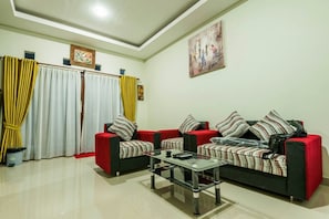 A living room with a sofa set, a coffee table, and curtains. - Beluran Serene Guesthouse (Tabanan)