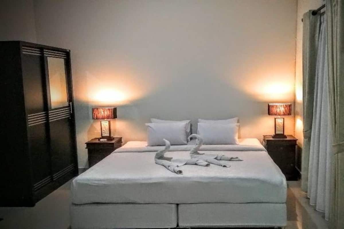A neatly made bed with white linens and two lamps on either side.