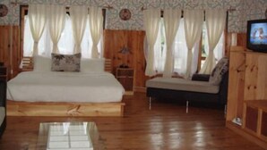 Una habitación con cama, sofá, televisión y piso de madera.