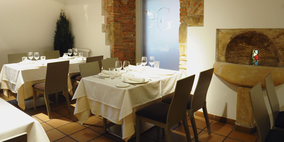 Un restaurante con mesas dispuestas para comer, una pared de ladrillo y un vitral.