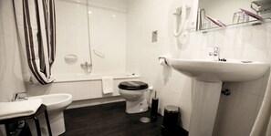 A modern bathroom with a bathtub, toilet, and sink. - Hotel Los Guardeses (Medio Cudeyo)