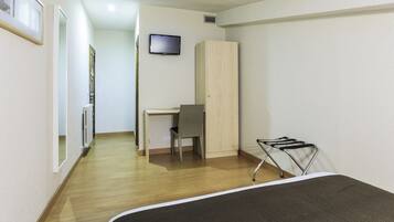 Una habitación con una cama, un escritorio, una silla, un televisor y un armario.