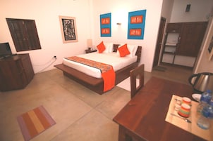 A bedroom with a bed, bedside tables, a desk, and a chair. There is a small rug on the floor and a picture on the wall.
