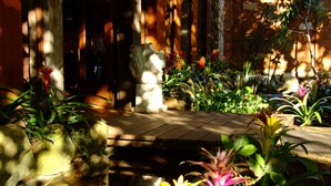 A garden with a stone pathway, various plants, and a statue. - Lis Bleu Pousada (Tiradentes)