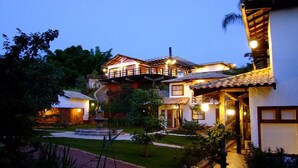 A multi-story house with a garden and a small pond. - Lis Bleu Pousada (Tiradentes)