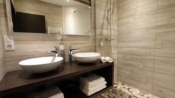 A modern bathroom with two sinks, a shower, and a mirror.