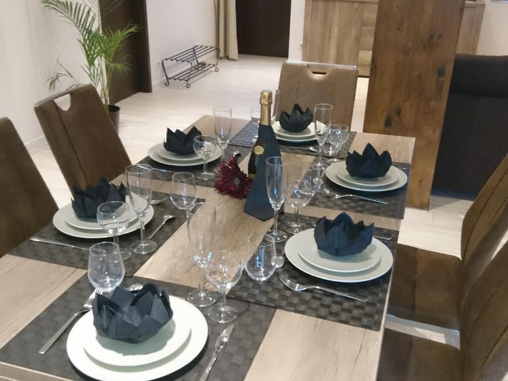 A dining table set with plates, glasses, and a bottle.
