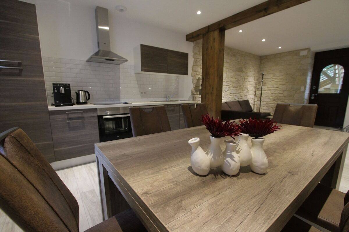 Een moderne keuken met een houten eettafel, witte vazen en accenten van stenen muren.