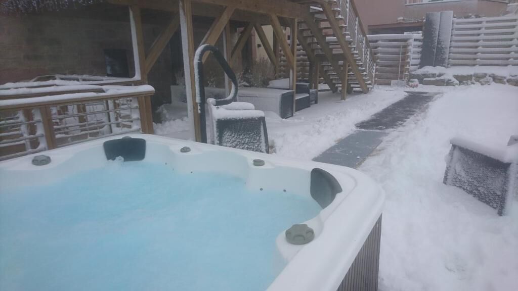 A hot tub surrounded by snow-covered steps and a wooden deck.