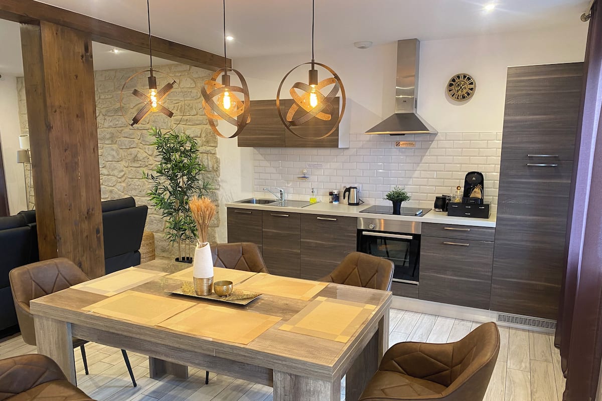 Een moderne keuken met donkere kastjes, een centraal eiland en hanglampen.