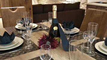 A dining table set for a meal with a bottle of champagne, clear glasses, and folded napkins.