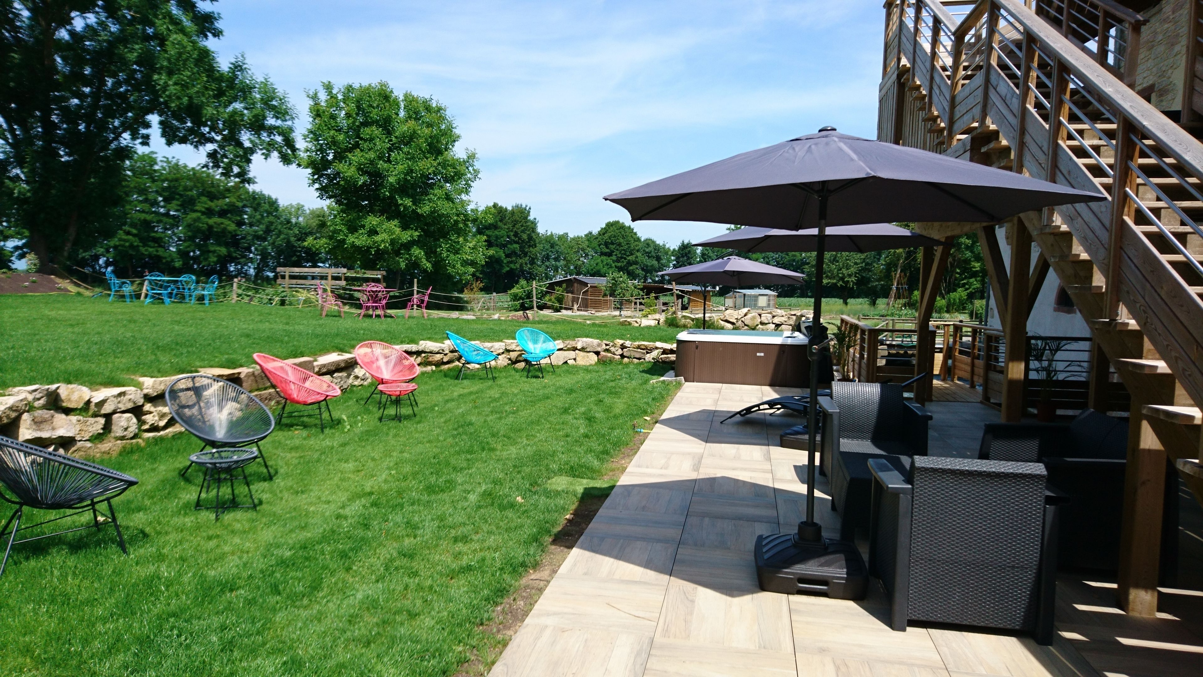 An outdoor patio area with seating, a hot tub, and a wooden staircase.