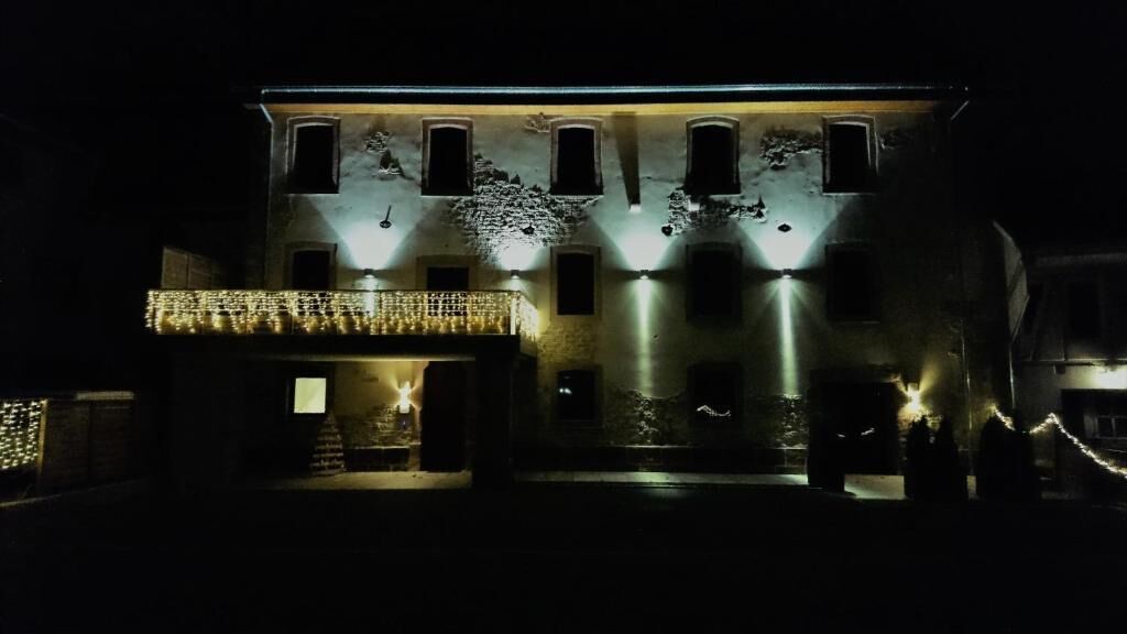 A building with multiple windows, a balcony with lights, and a gated entrance.