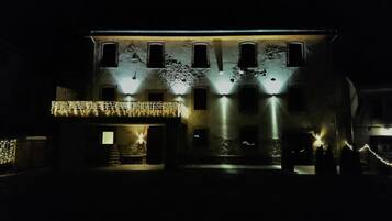 A building with multiple windows, a balcony with lights, and a gated entrance.