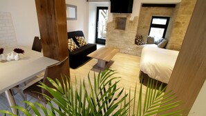Un salon moderne avec une cheminée en pierre, un canapé, un lit et un coin repas comprenant une table et des chaises.