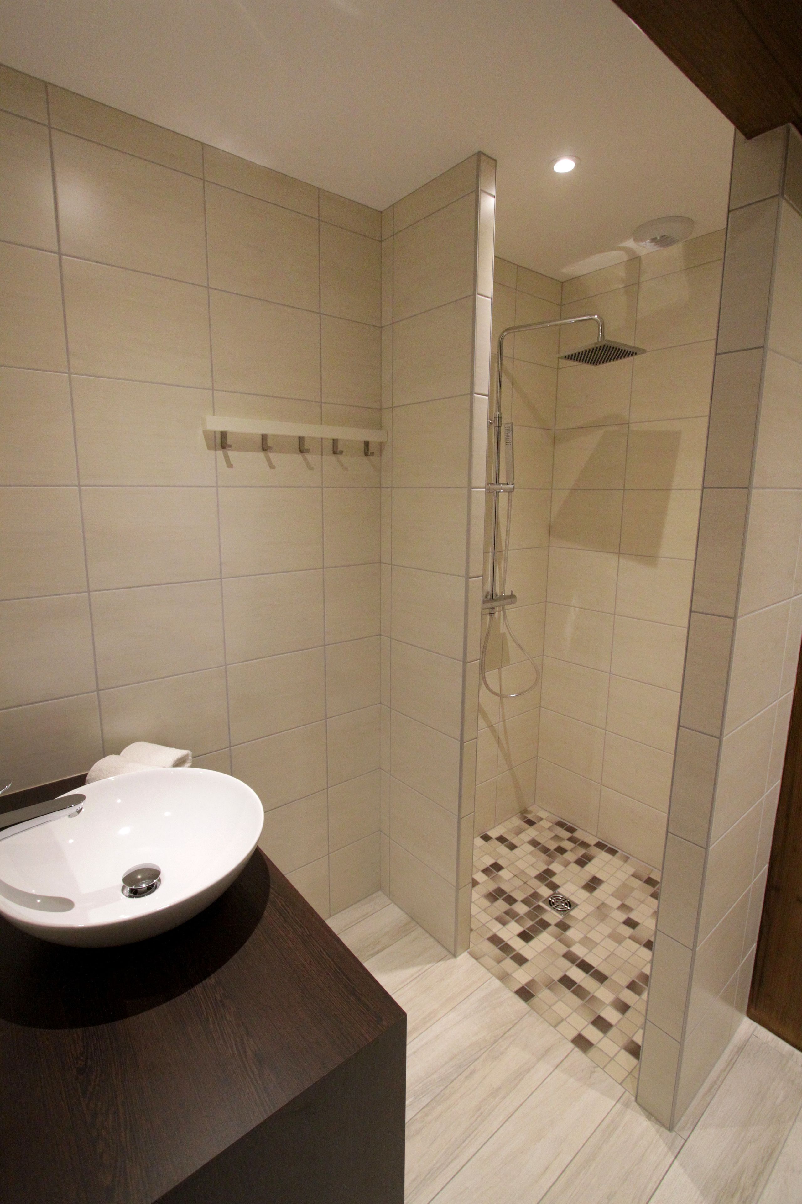 Une salle de bain moderne avec une douche à parois de verre, un lavabo rond et un sol carrelé.