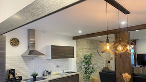 Une cuisine moderne avec un mur en pierre, des meubles en bois et un coin repas comprenant une table et des chaises.
