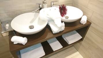 Une salle de bain avec deux lavabos, un miroir et un porte-serviettes où sont pliées des serviettes.