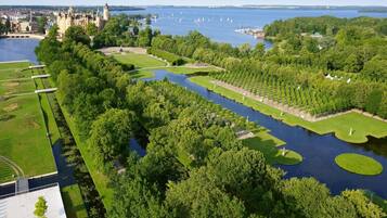 An aerial view of a park with a river, a castle, and a lake with sailboats.