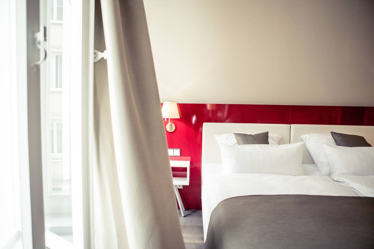 A hotel room with a bed, a nightstand, and a lamp.