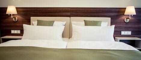A double bed with a wooden headboard, two bedside lamps, and a green throw blanket.