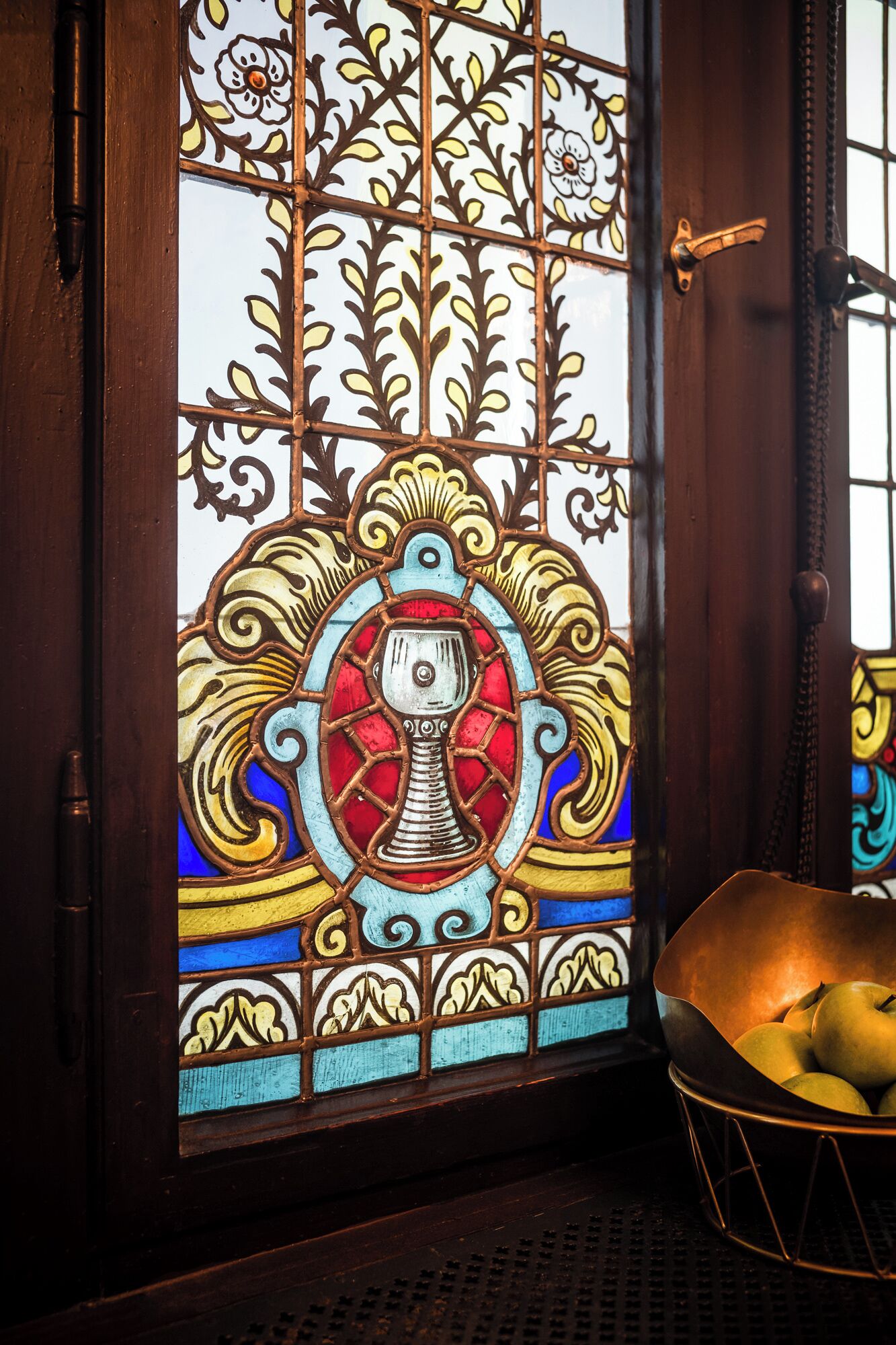 A stained glass door with intricate floral patterns and a central emblem.