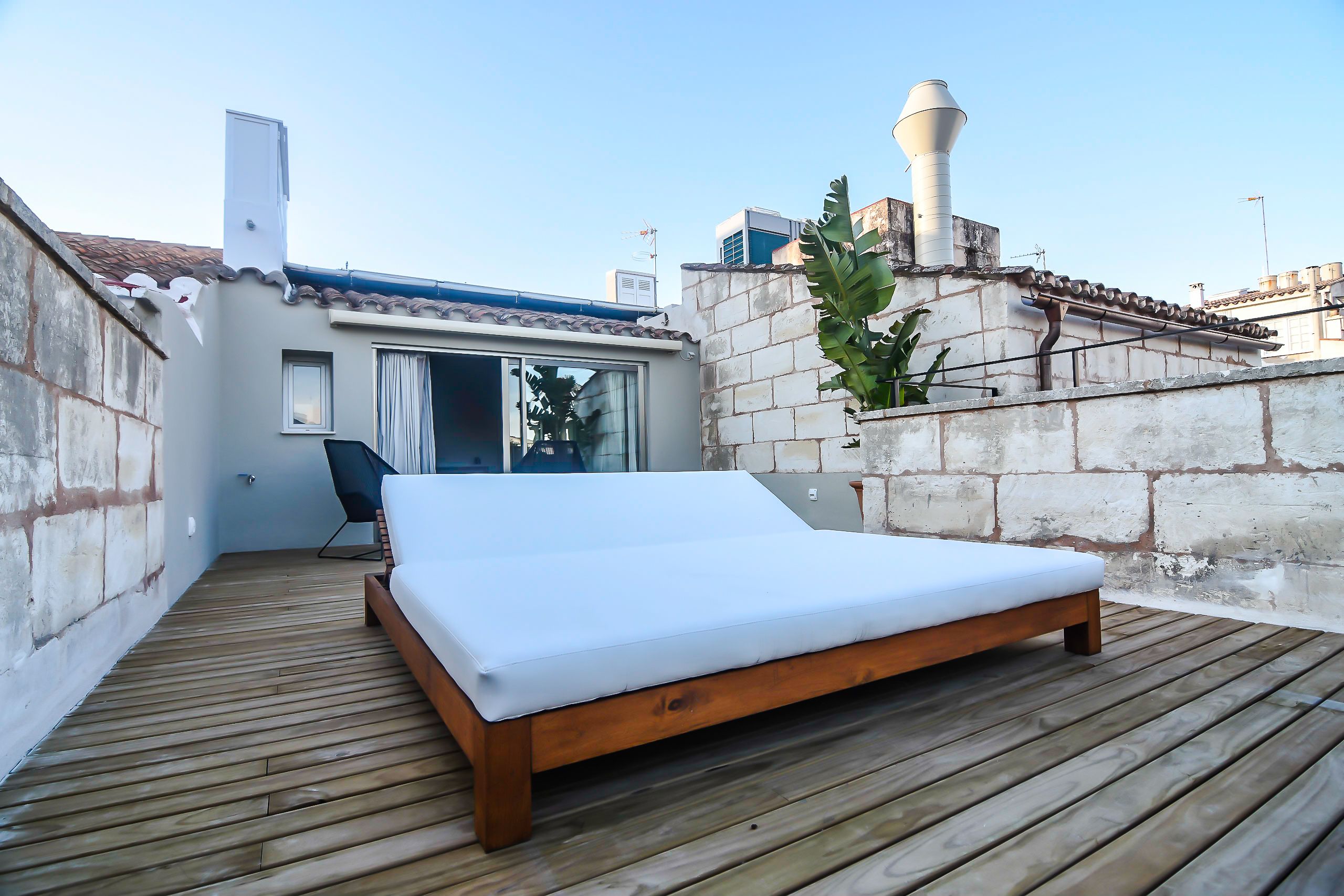 Une terrasse en bois avec un lit simple, une chaise et une petite table.