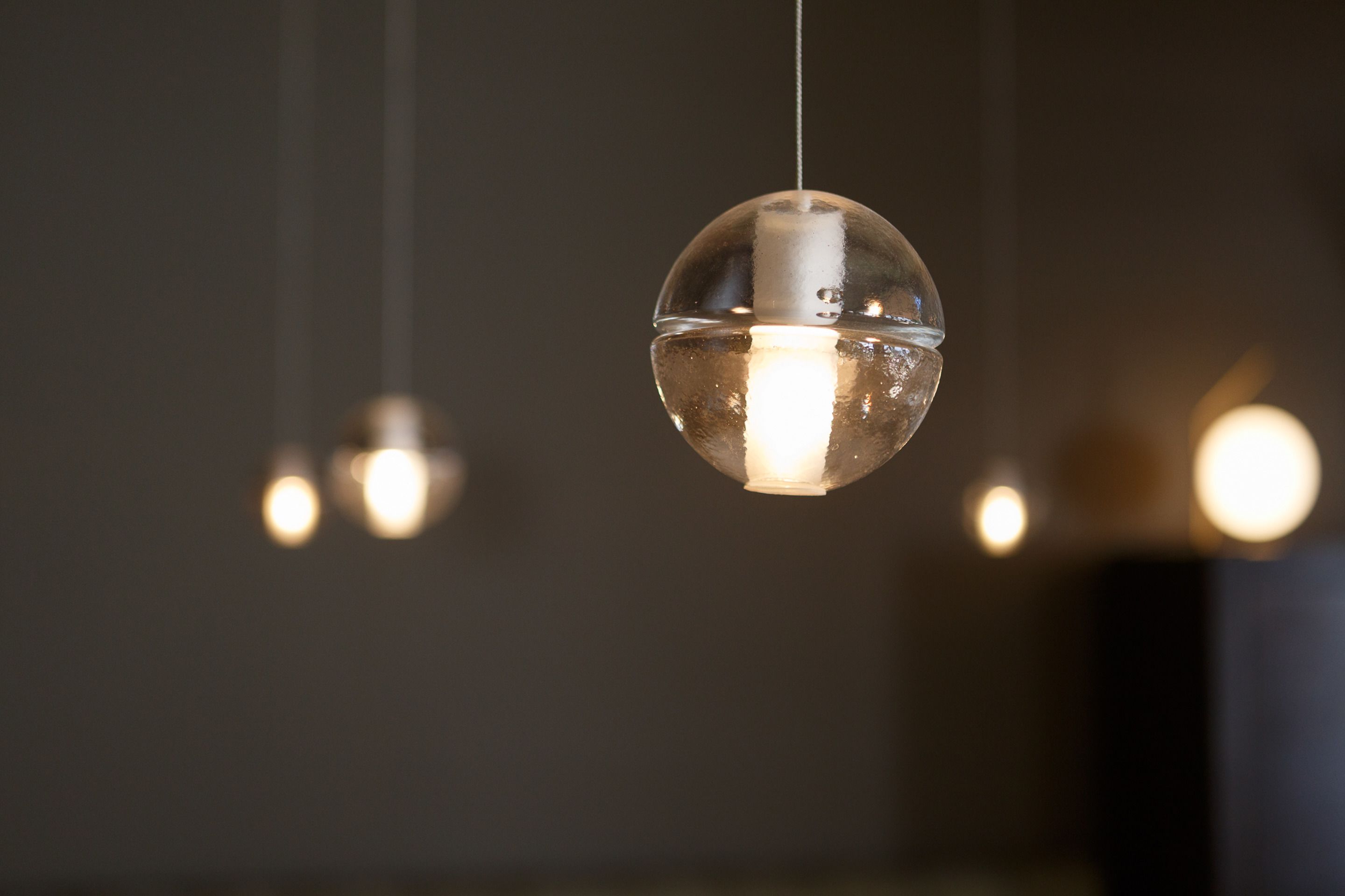 A spherical pendant light fixture with a visible filament bulb.