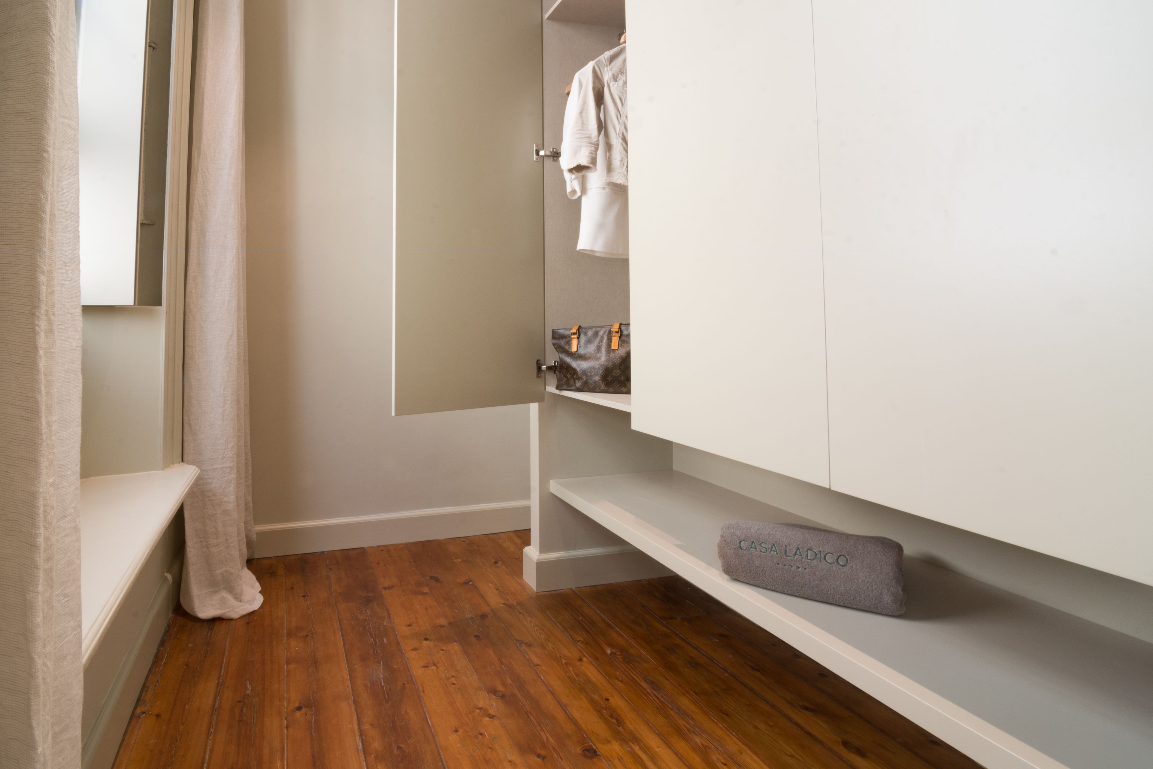 Un baño moderno con suelo de madera, tocador blanco y barra para toallas.