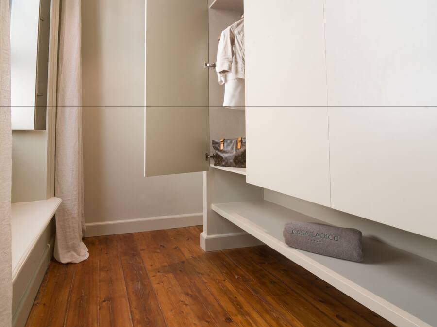 A modern bathroom with wooden flooring, a white vanity, and a towel rack.