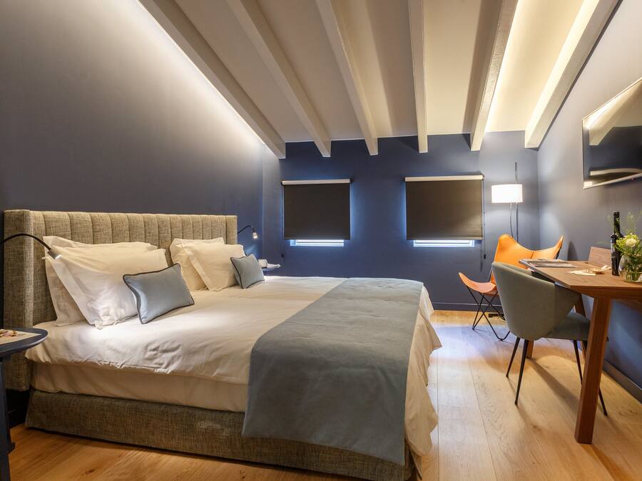 Una habitación de hotel moderna con una cama grande, un escritorio y una silla.