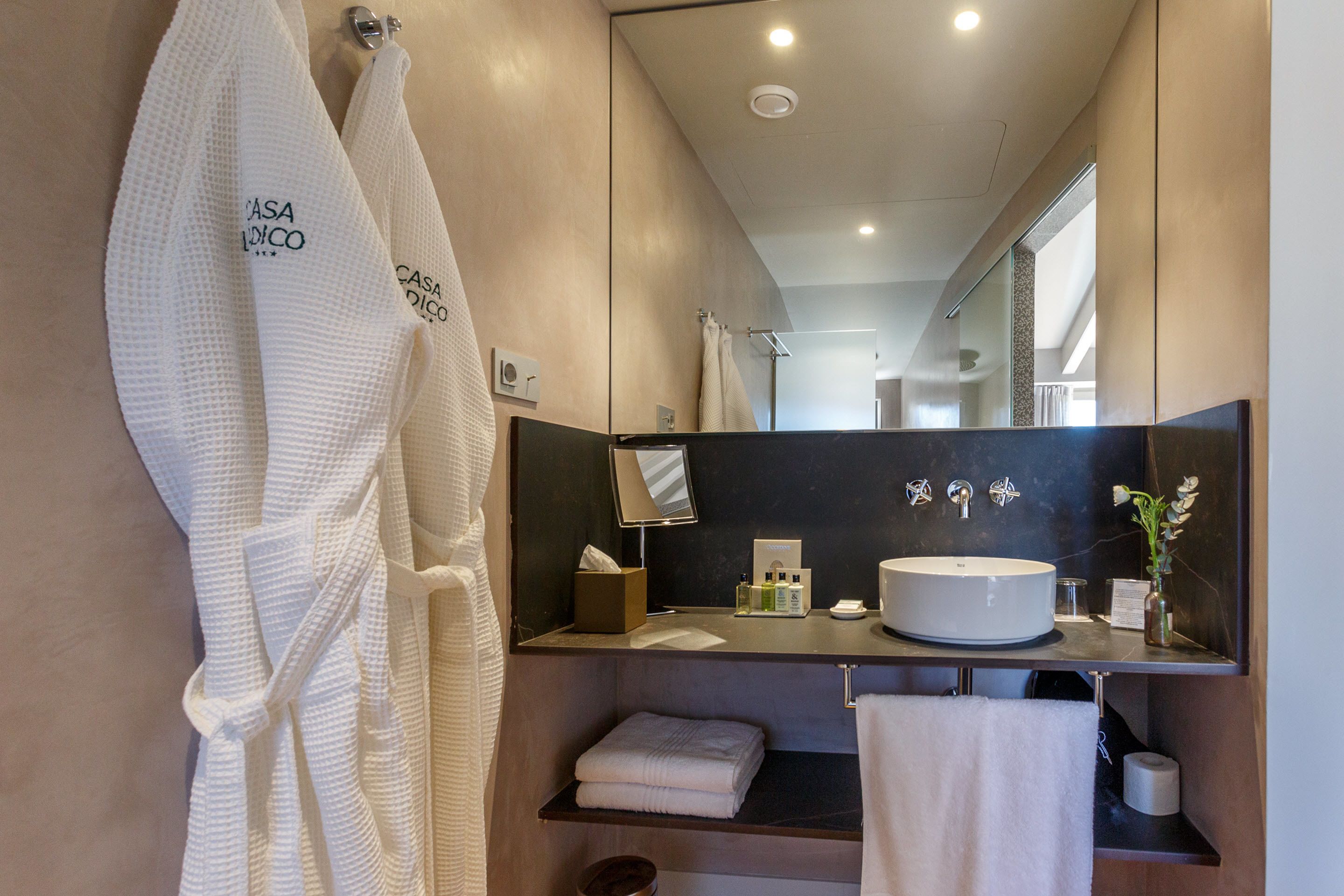 A modern bathroom with a large mirror, a round sink, and a towel rack.