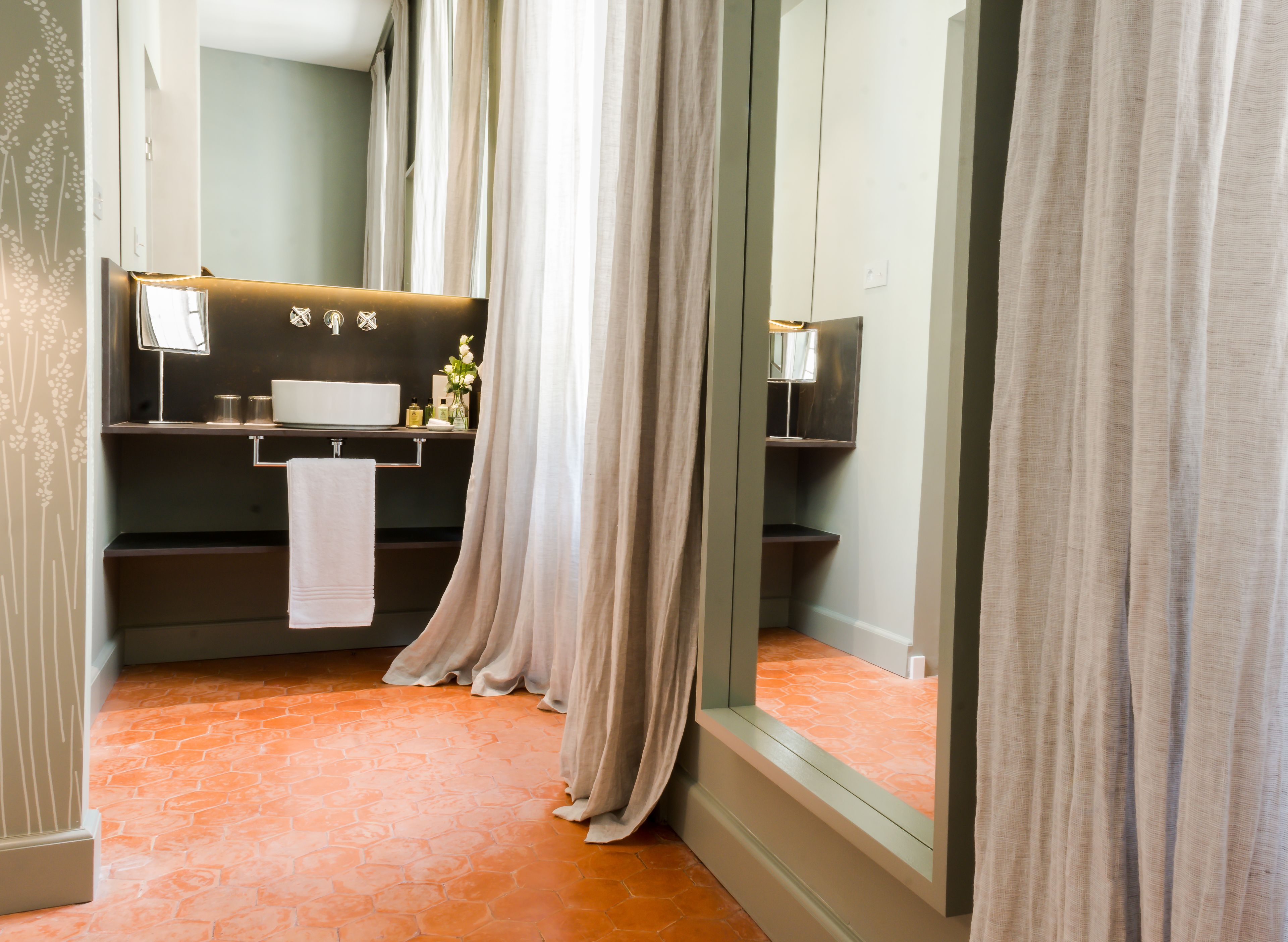 A modern bathroom with a large mirror, a sink, and a towel hanging on the wall.