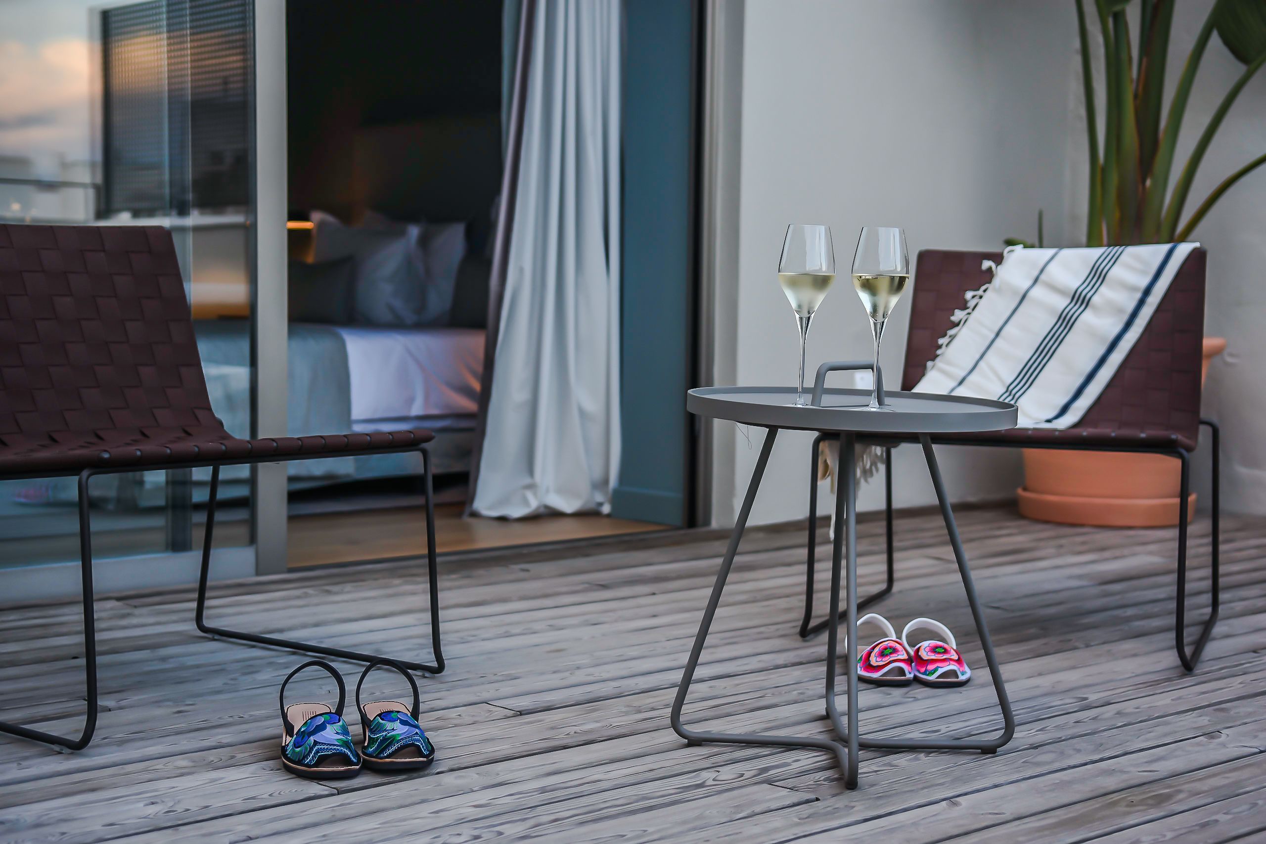 Una terraza de madera con una mesa, dos sillas y un par de zapatillas.