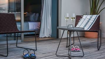 Una terraza de madera con una mesa, dos sillas y un par de zapatillas.