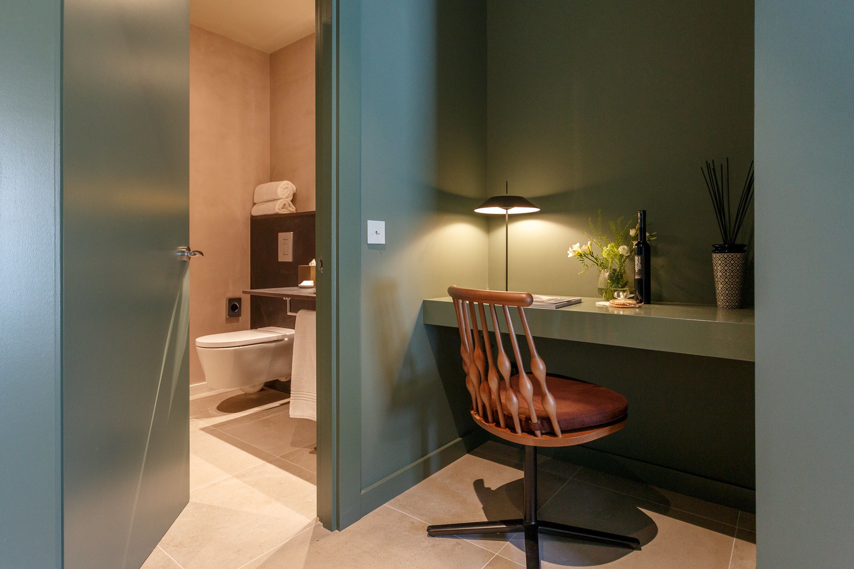 Un baño moderno con inodoro, lavamanos y una silla.