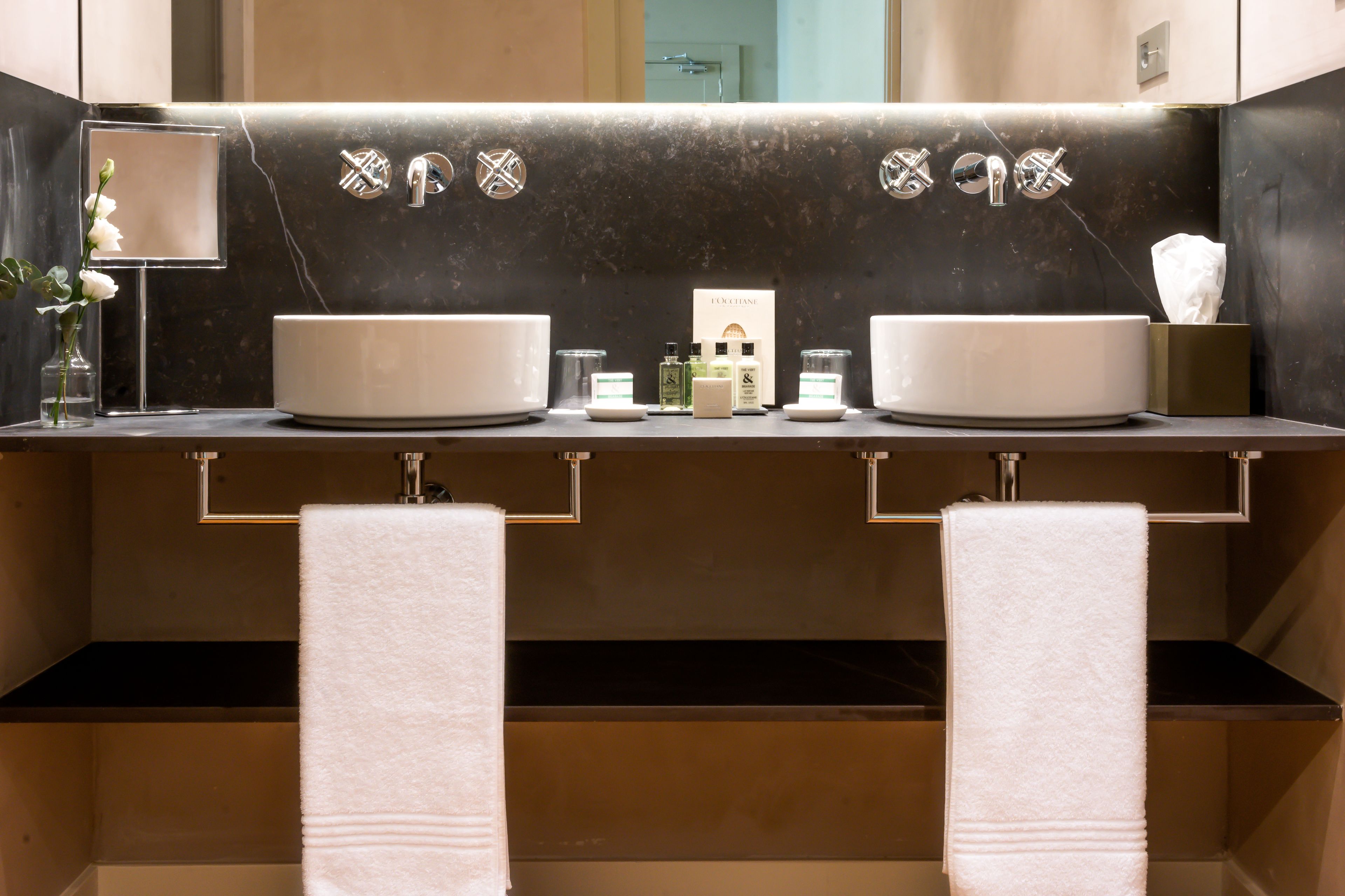 A modern bathroom with two sinks, a mirror, and a towel rack.