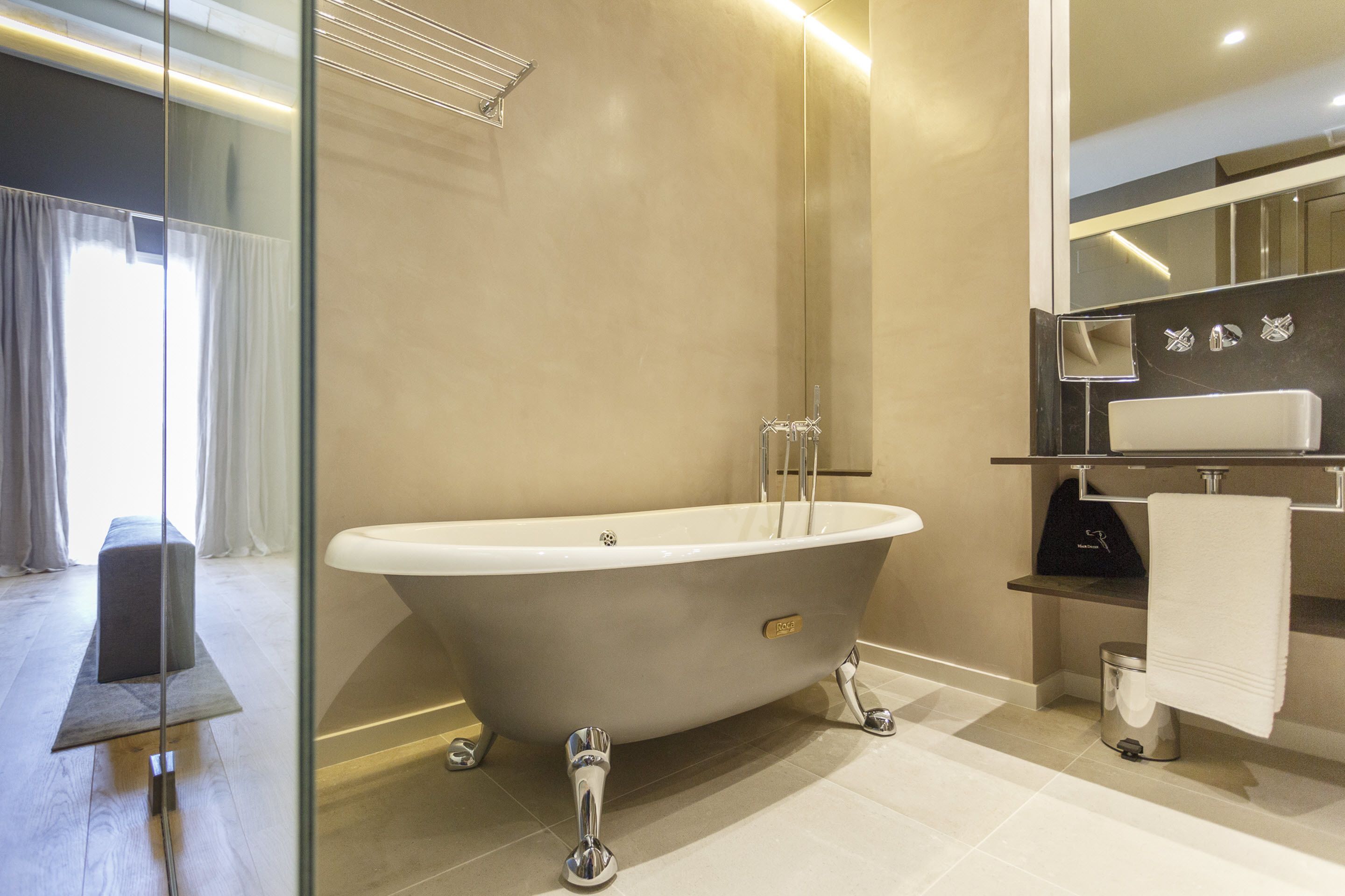 A modern bathroom with a freestanding bathtub, a glass shower enclosure, and a vanity with a mirror and towel rack.