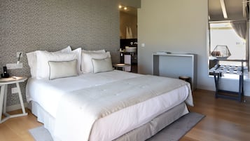 Un dormitorio moderno con una cama grande, mesitas de noche, un escritorio y vistas al exterior.