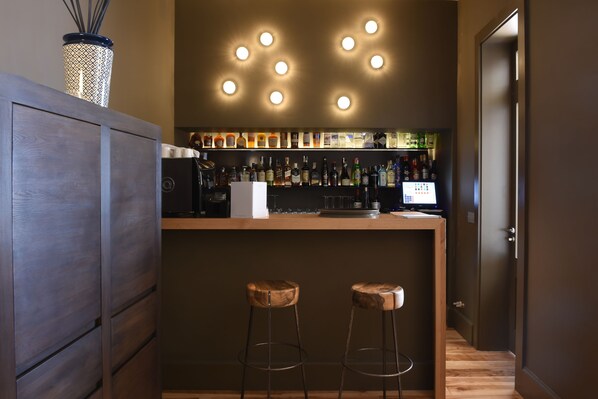 Zona de bar con taburetes, barra y una variedad de botellas.