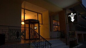 Entrada de hotel con una escalera, puerta de vidrio y un letrero con el nombre del hotel.