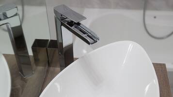 Un baño moderno con un lavamanos ovalado blanco, grifo cromado y un espejo encima.