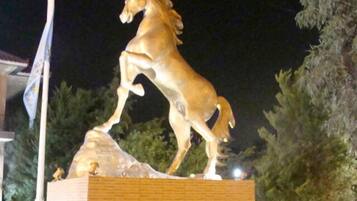 Una statua dorata di un cavallo su un piedistallo, con un'asta di bandiera a sinistra.
