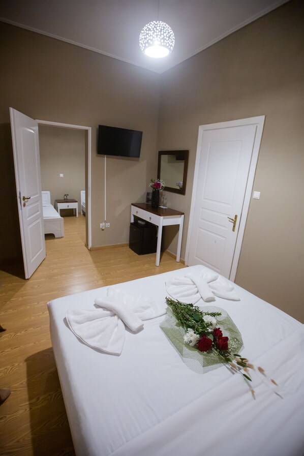 Una habitación de hotel con una cama, un escritorio, un televisor y una puerta.