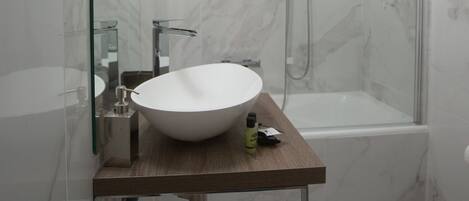 Un baño moderno con ducha de vidrio, un lavabo blanco y una bañera.