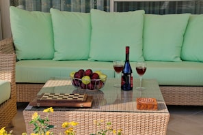 A wicker table with a chessboard, a bottle of wine, glasses, and a fruit bowl. - Villa Metaxas (Malevizi)