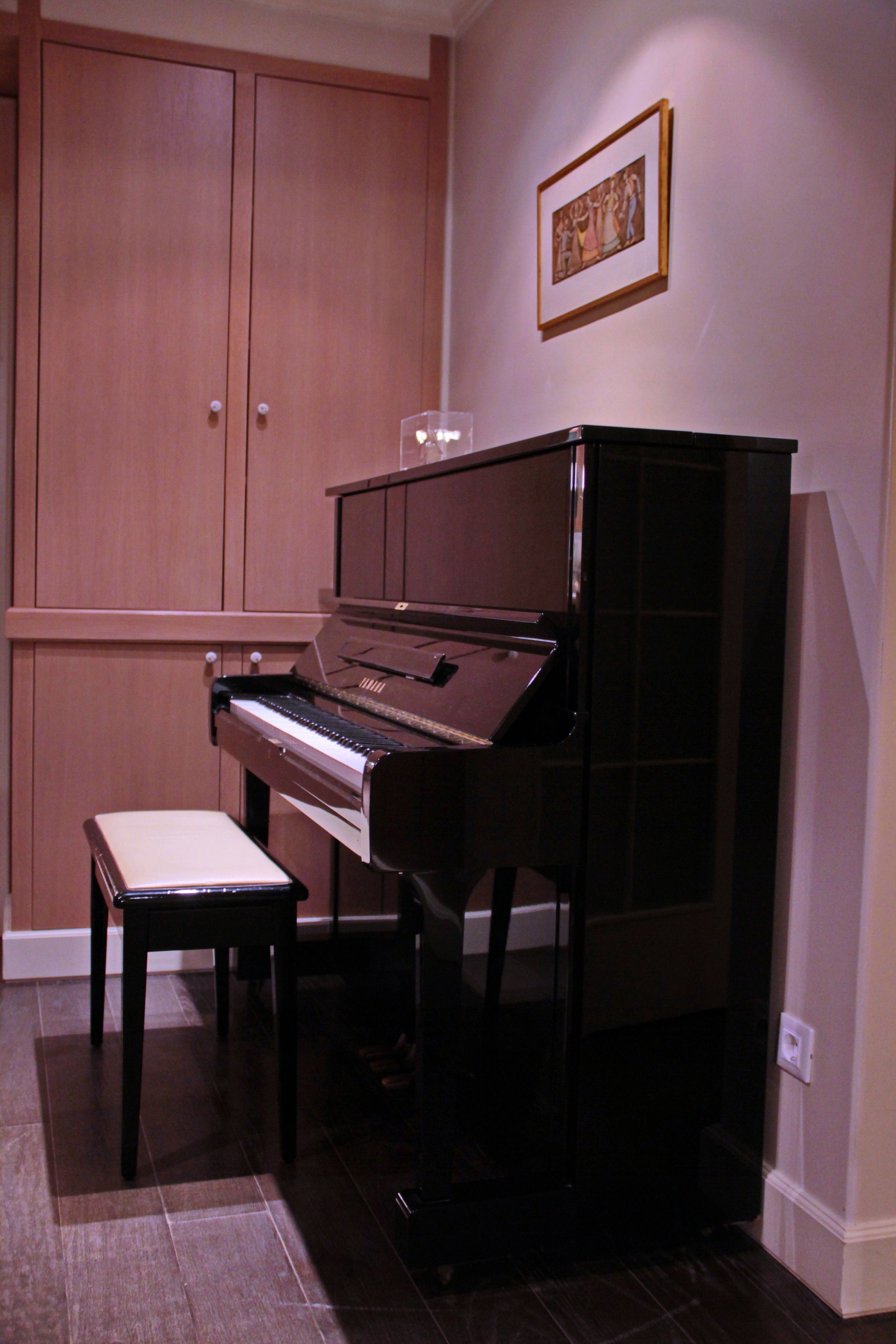 Un piano en una habitación con armarios de madera y un cuadro en la pared.
