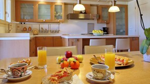 A breakfast setting with a table set for two, featuring a variety of fruits, a slice of pizza, and a cup of coffee. - Villa Metaxas (Malevizi)