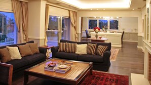 A living room with a dark-colored sofa, a coffee table with books, and a red patterned rug. - Villa Metaxas (Malevizi)